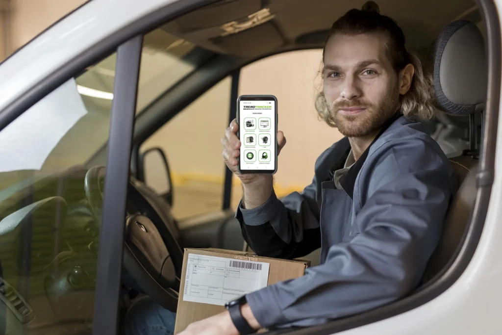 man sat in a van holding a smartphone showing the treadtracker app